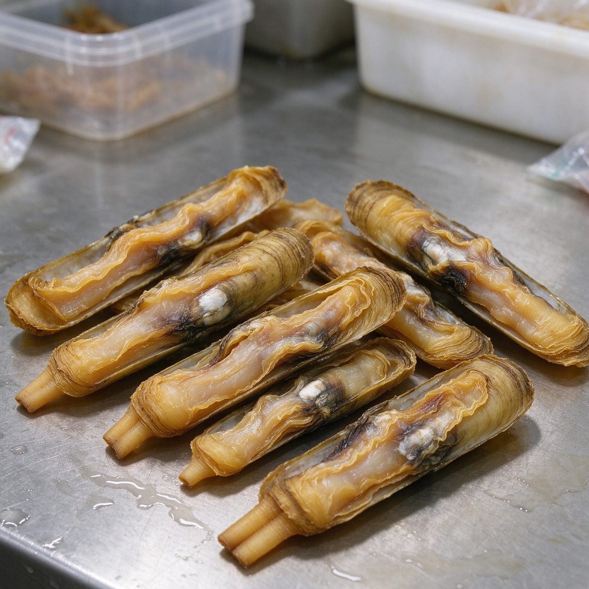 Bamboo clams with ridged olive shells on a metal tray