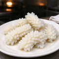 Scored squid pieces with a cross-hatch pattern on a plate