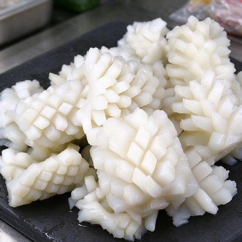 Scored squid pieces with a cross-hatch pattern on a plate