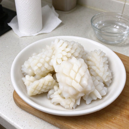 Scored squid pieces with a cross-hatch pattern on a plate