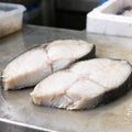 Thick halibut steaks with dark skin on a steel tray