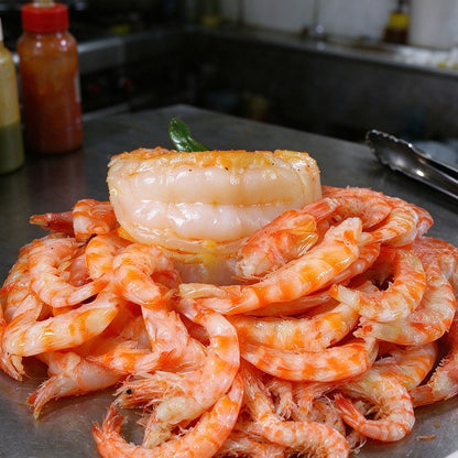 Pile of cooked orange shrimp on a white plate