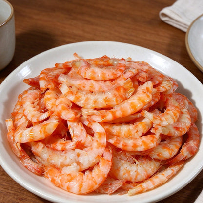 Pile of cooked orange shrimp on a white plate